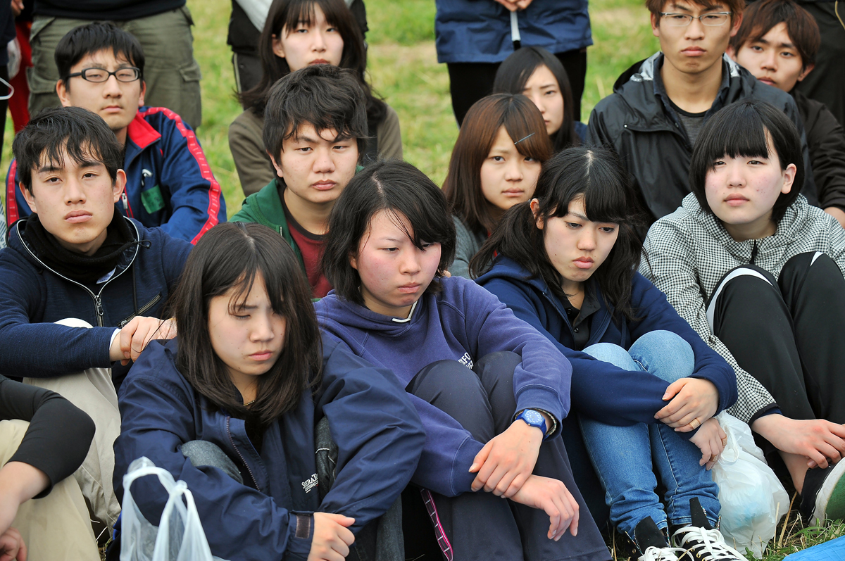 沈み込んだ表情で、遺骨収集についての説明を聞く学生たち