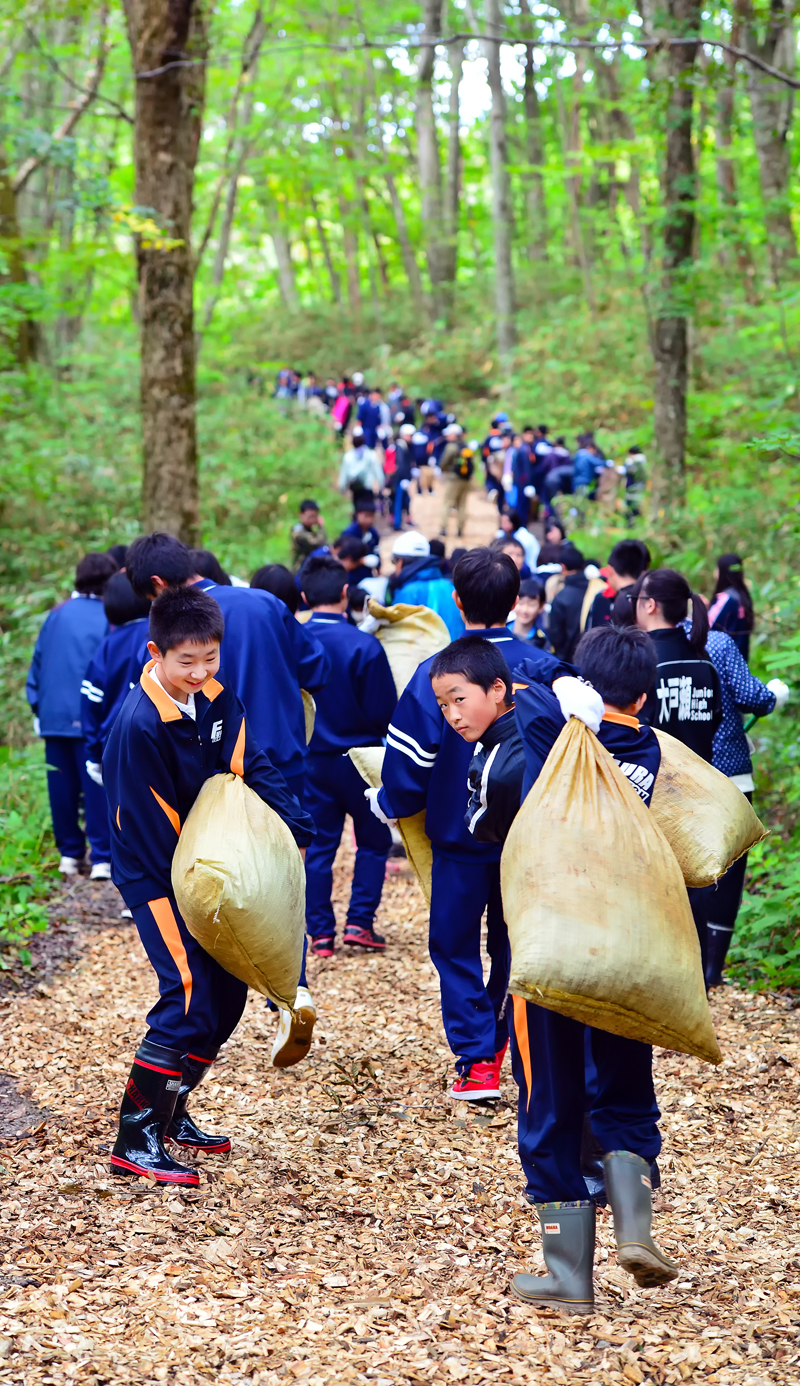 森の奥までチップを運ぶ中学生たち